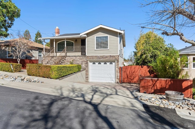 view of front of house featuring concrete driveway, stone siding, a chimney, an attached garage, and fence