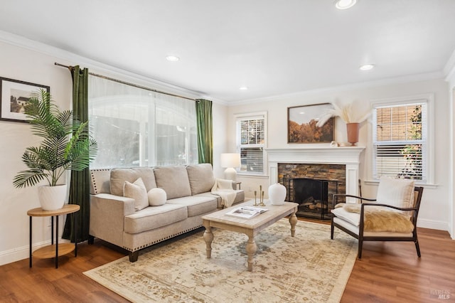 living area featuring ornamental molding, a stone fireplace, dark wood-style flooring, and baseboards