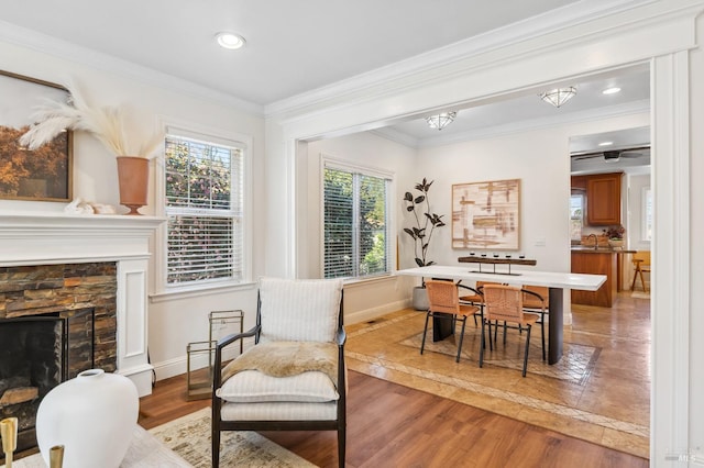 sitting room featuring baseboards, a stone fireplace, light wood-style flooring, and crown molding