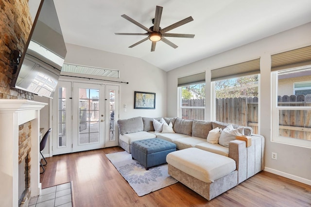 living area with lofted ceiling, a fireplace, ceiling fan, and wood finished floors