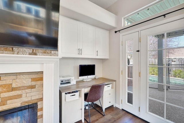 office with dark wood-type flooring, built in study area, and a fireplace