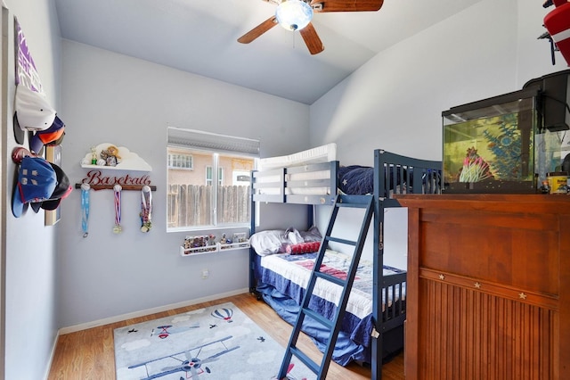 bedroom featuring lofted ceiling, ceiling fan, baseboards, and wood finished floors