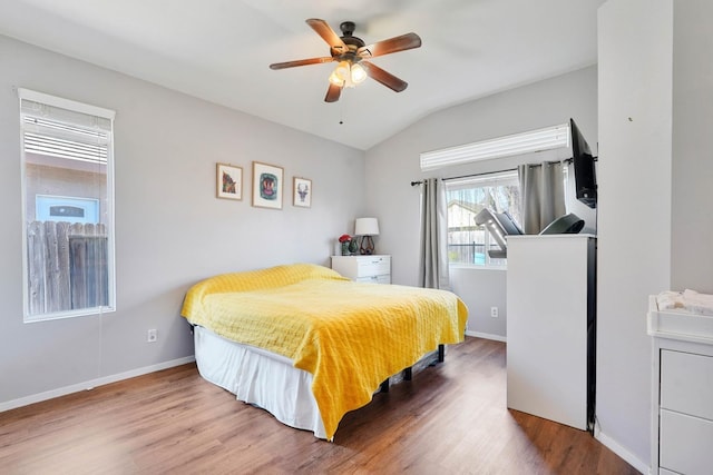 bedroom with ceiling fan, vaulted ceiling, baseboards, and wood finished floors