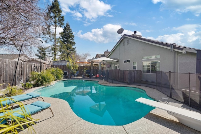 view of swimming pool featuring a diving board, a patio area, a fenced backyard, and a fenced in pool