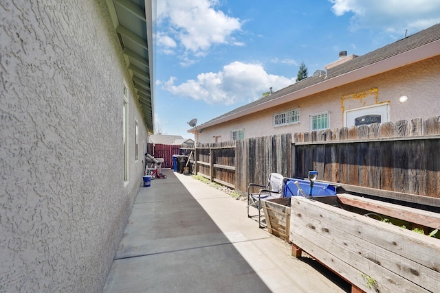 view of side of home featuring a patio area, fence, and stucco siding