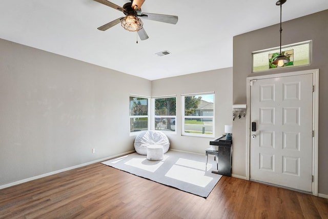 entrance foyer with a ceiling fan, visible vents, baseboards, and wood finished floors