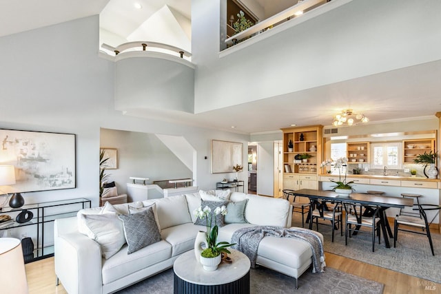 living area featuring light wood-style flooring, a high ceiling, and ornamental molding