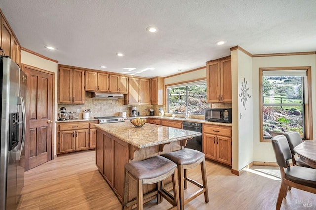 kitchen featuring backsplash, crown molding, under cabinet range hood, and black appliances