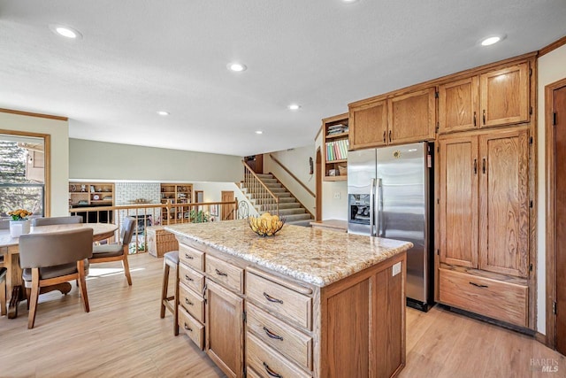 kitchen featuring a kitchen island, brown cabinets, light wood-style floors, stainless steel refrigerator with ice dispenser, and recessed lighting