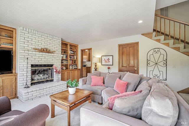 carpeted living area featuring built in shelves, stairway, a brick fireplace, and a textured ceiling