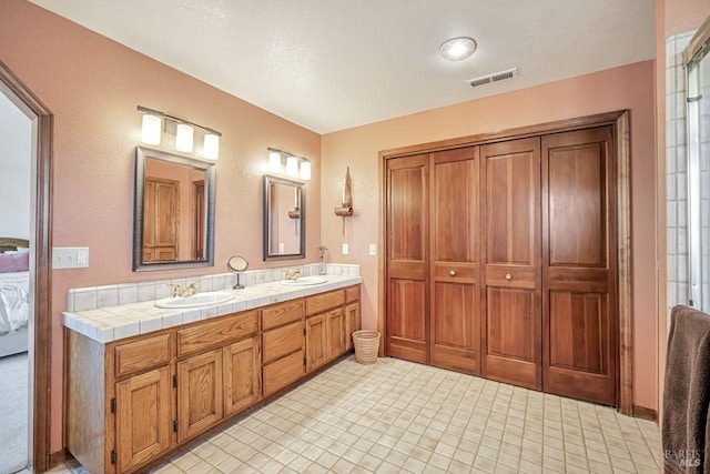 bathroom with double vanity, visible vents, a sink, and ensuite bathroom