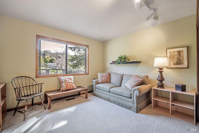 living room with carpet floors, visible vents, baseboards, and track lighting