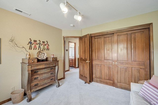 bedroom featuring track lighting, light colored carpet, visible vents, and baseboards