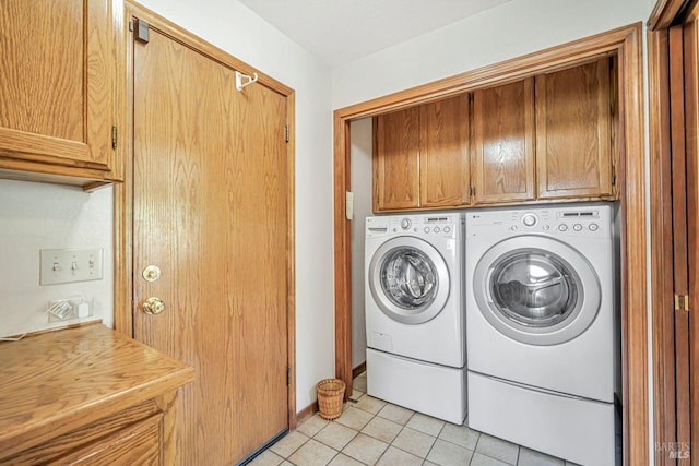 clothes washing area with cabinet space, light tile patterned floors, and washer and dryer