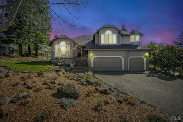 view of front of property with a garage, driveway, and stairway