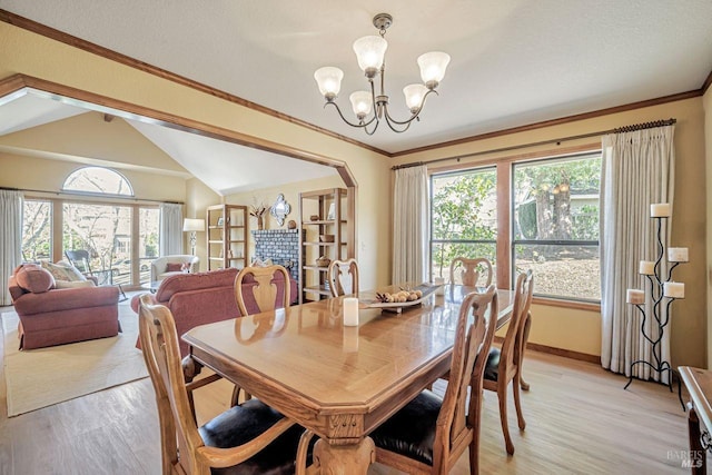 dining area featuring crown molding, lofted ceiling, light wood-style flooring, and an inviting chandelier