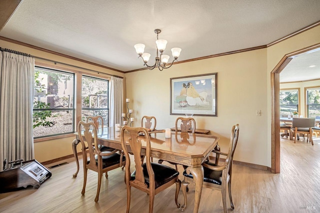 dining space with a healthy amount of sunlight, light wood-style flooring, and ornamental molding