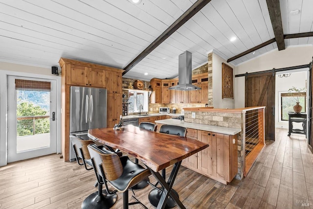 kitchen with island exhaust hood, light countertops, lofted ceiling with beams, a barn door, and freestanding refrigerator