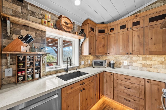 kitchen with tasteful backsplash, lofted ceiling, light countertops, stainless steel dishwasher, and a sink