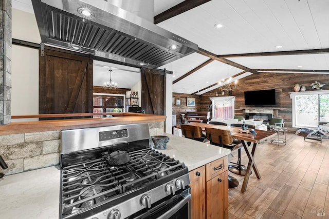 kitchen featuring vaulted ceiling with beams, a notable chandelier, stainless steel gas range oven, and a barn door