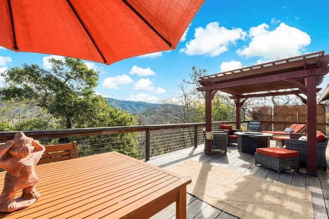 wooden deck with a mountain view, a fire pit, and a pergola