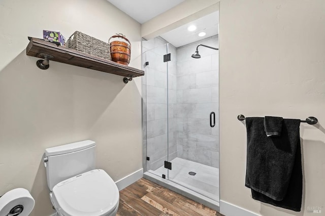 full bath featuring toilet, a shower stall, baseboards, and wood finished floors