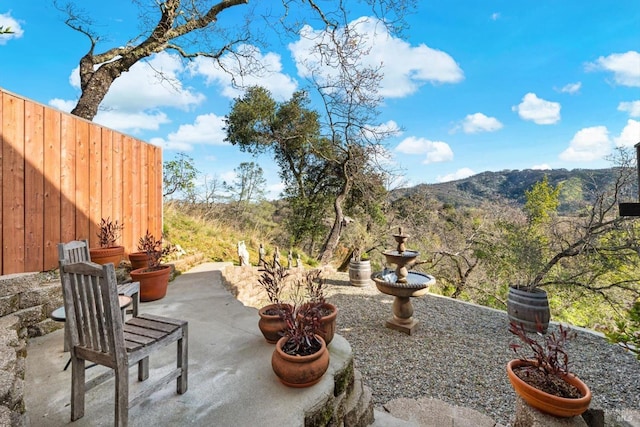 view of patio / terrace featuring fence and a mountain view