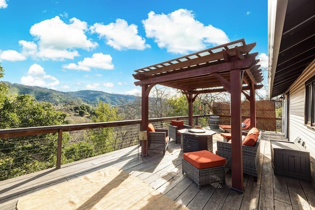 wooden deck with a fire pit, a mountain view, and a pergola