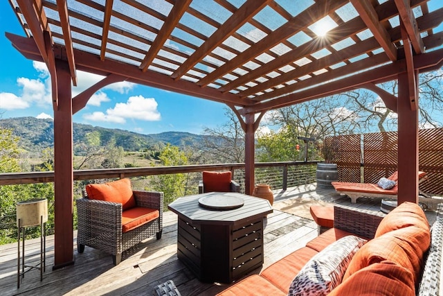 wooden deck with an outdoor living space with a fire pit, a mountain view, and a pergola