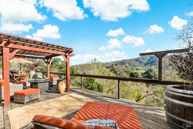 deck featuring a wooded view and a pergola