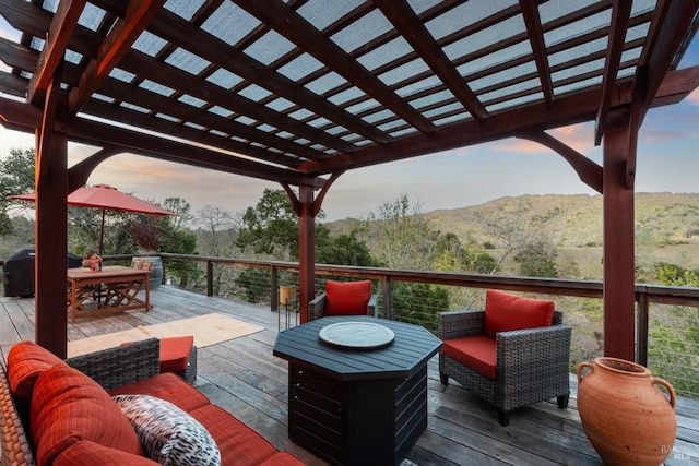 deck featuring outdoor dining space, an outdoor hangout area, a forest view, and a pergola