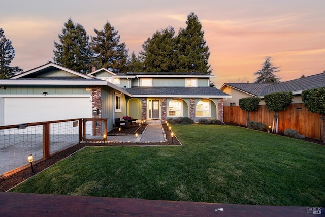 view of front of house featuring a garage, solar panels, fence, driveway, and a front lawn