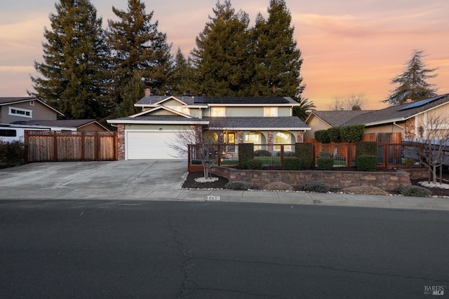 traditional-style house with an attached garage, driveway, and a fenced front yard