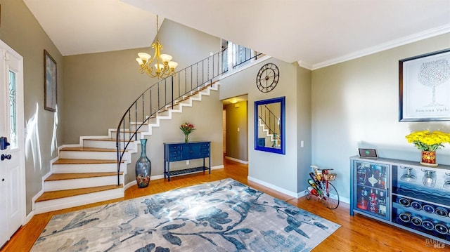 entryway featuring baseboards, stairway, wood finished floors, an inviting chandelier, and crown molding