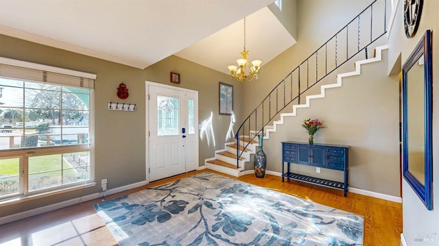 foyer featuring a notable chandelier, wood finished floors, baseboards, stairway, and crown molding