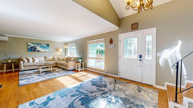 foyer with ornamental molding, vaulted ceiling, wood finished floors, a chandelier, and baseboards