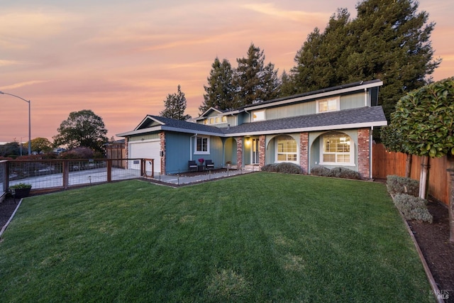 traditional-style home with a garage, a yard, brick siding, and a fenced backyard