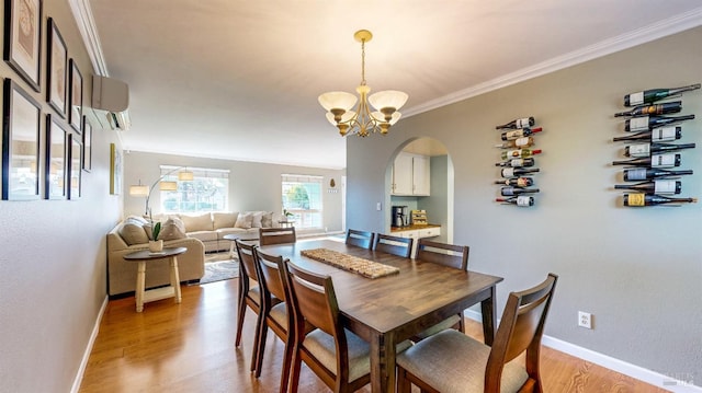 dining space featuring baseboards, arched walkways, crown molding, light wood-type flooring, and a chandelier