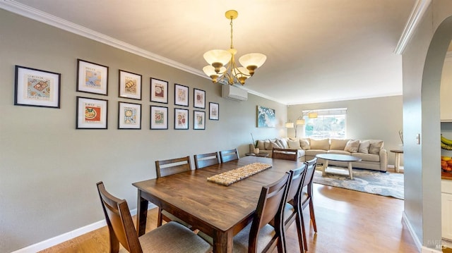 dining area with crown molding, a notable chandelier, light wood-type flooring, a wall mounted air conditioner, and baseboards