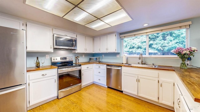 kitchen featuring stainless steel appliances, light countertops, a sink, and white cabinetry