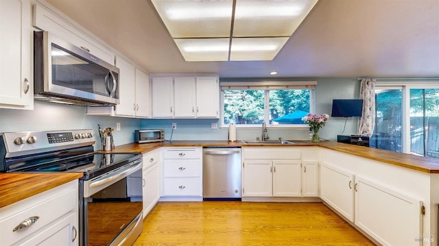 kitchen with white cabinets, light wood-style flooring, stainless steel appliances, and a sink