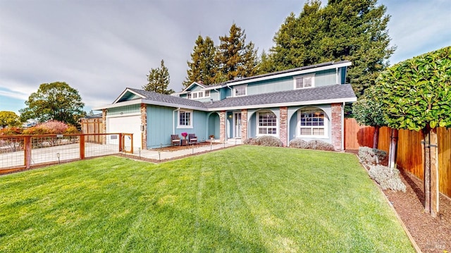 traditional home featuring a front lawn, roof with shingles, an attached garage, and a fenced backyard