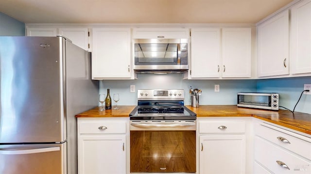 kitchen featuring stainless steel appliances, a toaster, white cabinets, and wooden counters