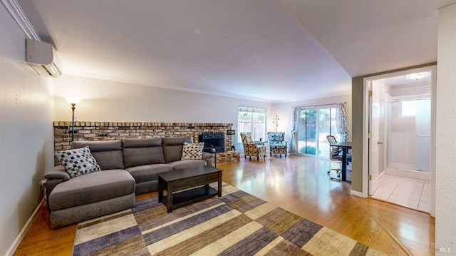 living area with light wood-type flooring, a fireplace, baseboards, and a wall mounted AC