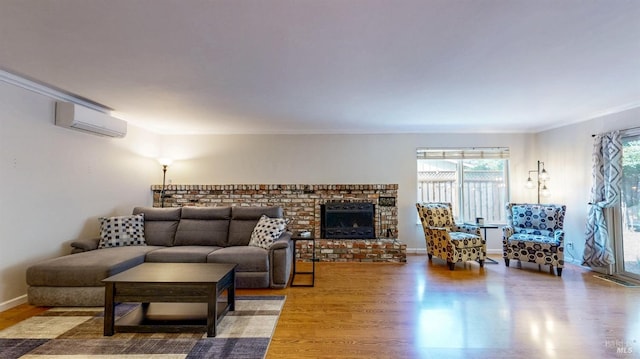 living room featuring a wall unit AC, a fireplace, wood finished floors, baseboards, and crown molding