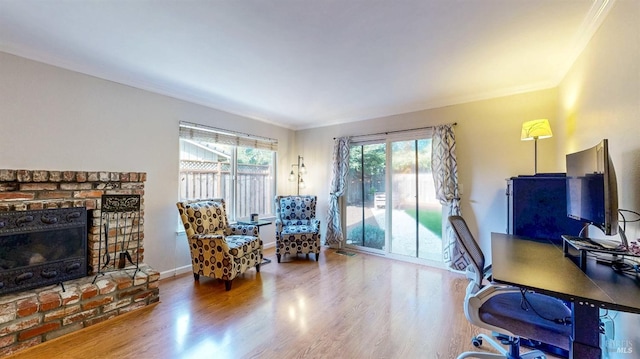 office area featuring ornamental molding, a brick fireplace, wood finished floors, and baseboards