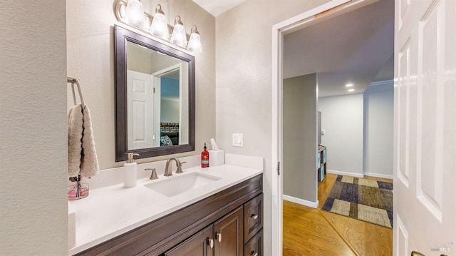 bathroom with vanity, baseboards, wood finished floors, and ensuite bathroom