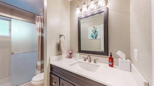 bathroom featuring toilet, a textured wall, a shower with shower curtain, and vanity