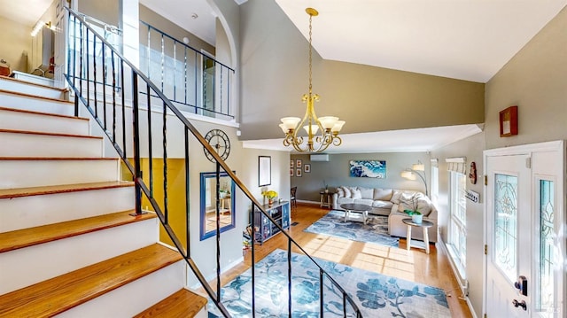 staircase featuring baseboards, high vaulted ceiling, wood finished floors, and a notable chandelier