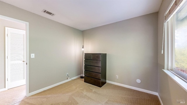 spare room with baseboards, visible vents, and light colored carpet